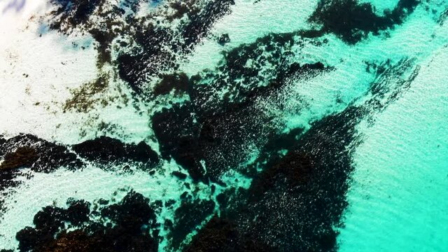 Straight Down Drone Shot Of Hyams Beach, Flying Over The Turquoise Ocean With Waves Crashing On The Rocks And White Sandy Beach