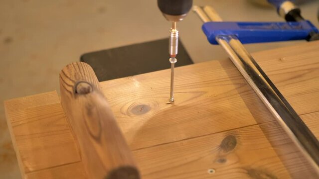 Carpenter fixing termo pine plank to wood foundation with a single screw. Termowood plan fixed in place with hand clamp.