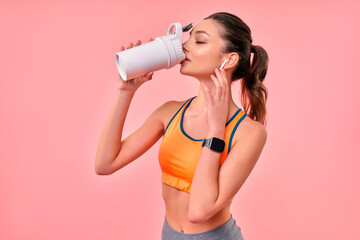 Cute athletic girl in sportswear with protein shake isolated on pink background. Sports, yoga,...