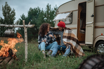 Obraz premium Couple in a checkered plaid roasting marshmallows on fire near the trailer home.