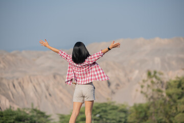 fit young woman hiking in the mountains standing on a rocky summit ridge with backpack and pole looking out over landscape. hiker with backpack relaxing on top of a mountain and enjoying valley view.