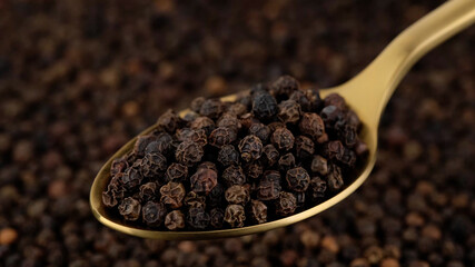 peppercorn in golden spoon and on black background. Flavorful and aromatic black pepper