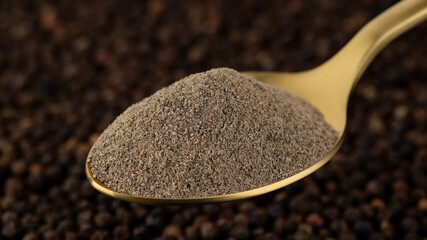 ground black pepper in golden spoon and peppercorn on background. Flavorful and aromatic black pepper