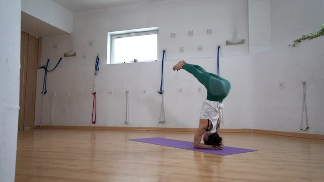 Woman performing Supported Headstand with Splits pose in room