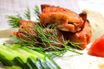Juicy pork shish kebab with vegetables and herbs on a plate.
