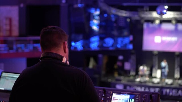 T&eacute;cnico de sonido de espaldas en su puesto de trabajo configurando la mesa 