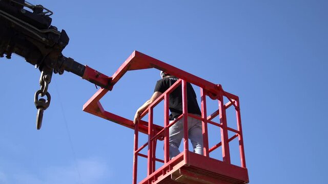 Hombre montado en un a grua elevadora colocando un drone en un cable