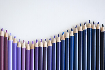 Many shades of blue and purple pencils lying on white background closeup