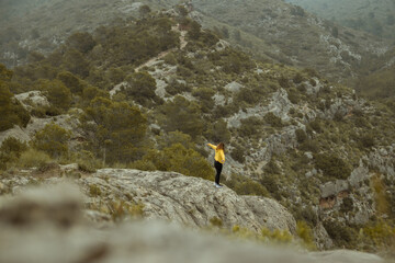 Woman with jacket in the distance on a mountain top with mist and raining in autumn