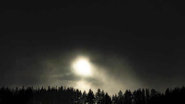 Timelapse. Thick dark clouds sweep over the sun and forest. A symbol of darkness and sorrow.