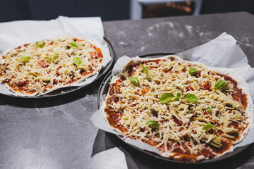 homemade vegan pizzas getting prepared on kitchen benchtop, healthy plant-based food
