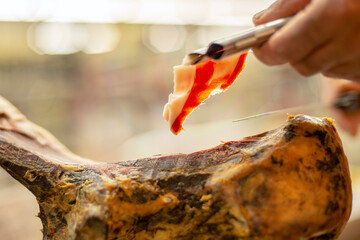 Close-up on person's hands slicing delicious cured cured ham carving