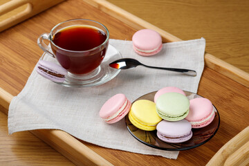 Cup of tea and colorful macaroons on a wooden tray. Morning tea and sweets