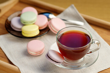 Cup of tea and colorful macaroons on a wooden tray. Morning tea and sweets