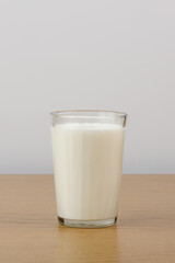 A glass of milk on a wooden table on a white background