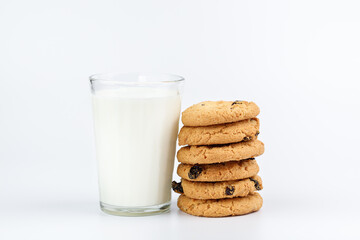 A glass of milk and cookies with raisins on a white background