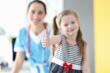 Little girl showing thumb up at doctor appointment closeup