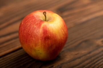 A fresh red apple on a rustic wooden table.