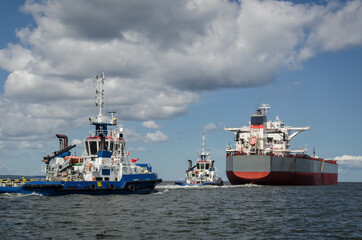 Fototapeta premium BULK CARRIER - The ship sails to sea with assistance of tugs