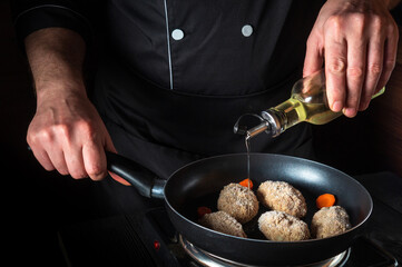 Cooking beef cutlets in a grill pan with the hands of a chef on a black background for copying the space text restaurant menu. Chef or cook adds oil