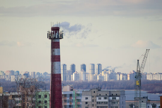 Brick chimney against the multistory buildings and sky in winter