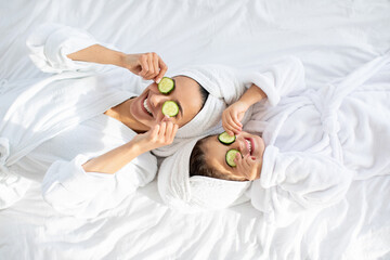 Top view of mother and daughter laying on bed - obrazy, fototapety, plakaty