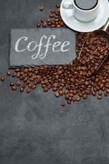 Background or texture made of roasted brown coffee beans and stone serving board with chalk handwritten sign