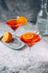 Fresh orange cocktail in martini glass with slice of orange on the table.