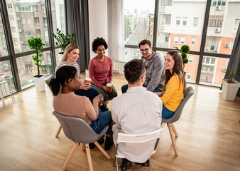 Diverse group of people sitting in circle in group therapy session.