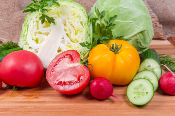 Different fresh vegetables and greens on wooden cutting board