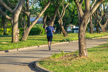 Fototapeta premium Young Asian man running in the green park