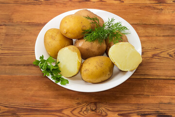 Potatoes boiled in their jackets and greens on rustic table