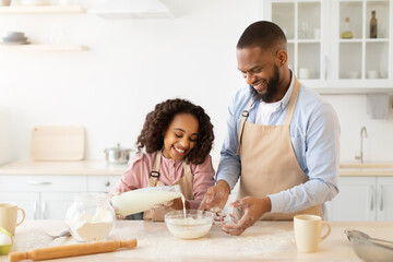 Obraz na płótnie Canvas Happy afro family preparing dough together in kitchen