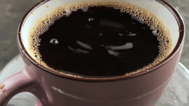 Espresso coffee drop into the filled Cup from the coffee machine in slow motion