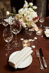 beautiful table setting for a romantic dinner with white bouquet and rose petals