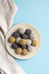 Energy balls lie on a large plate on a blue background, vertical orientation, close-up