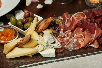 plate with thinly sliced ham, ham, blue cheese, parmesan and large olives