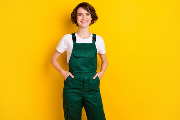 Photo of pretty cheerful girl put arms in pockets toothy smile look camera isolated on yellow color...
