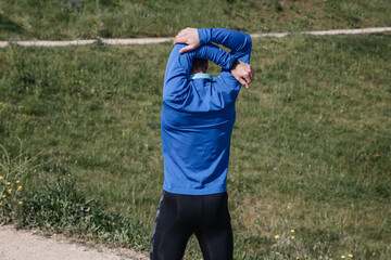Young runner stretching arms before running in the park
