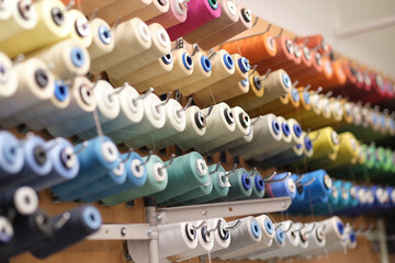 group of sewing threads in skeins. A bunch of large multicolored spools of thread. Atelier workshop. A set of colored threads for sewing on reels. - obrazy, fototapety, plakaty