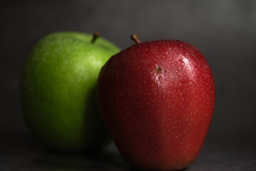 green and red apple on dark background