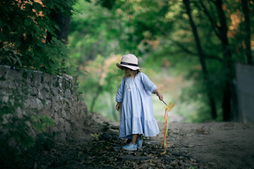 Happy childhood. Joyful cute caucasian child girl dancing and playing with magic wand in forest, Child conjures, children's fantasies. freedom and naturalness. Evening light in summer and soft focus