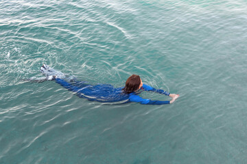 A girl in a wetsuit swimming in the sea. Aerial view. Healthy active lifestyle in summer vocation. Transparent water. Top view. 