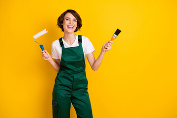 Photo of optimistic nice brown hair lady hold roller brush wear uniform isolated on yellow background