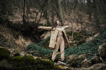 Freedom happy woman with hands up on view of forest with stones and trees background.
