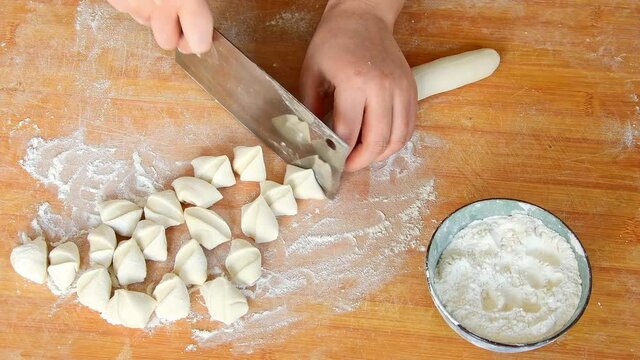 Close-up of a woman cutting dough into sections for making dumpling skins
