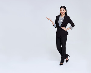 Smiling Confident Asian business woman with gesture of introduce isolated over gray background.