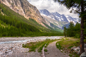 Fototapeta na wymiar Panorama della Val Veny col sentiero che costeggia il fiume e le vette delle montagne sullo sfondo. Alpi italiane. Valle d'Aosta. Italia