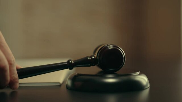 Judge is hitting gavel off a block in courtroom. Gavel is being struck to decide an auction or guilty verdict in court