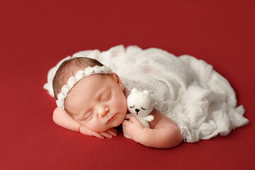 Newborn girl on a red background. Photoshoot for the newborn. A portrait of a beautiful newborn...